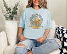 womens summer graphic tee in chambray.  The design says ain't no cure for the summertime blues in a vintage themed design.  The design is a big wave with a skeleton surfing with a guitar and some palm trees and flowers.