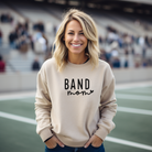 simple band mom design with heart attached to the word mom.  Band mom sweatshirt in the color sand.