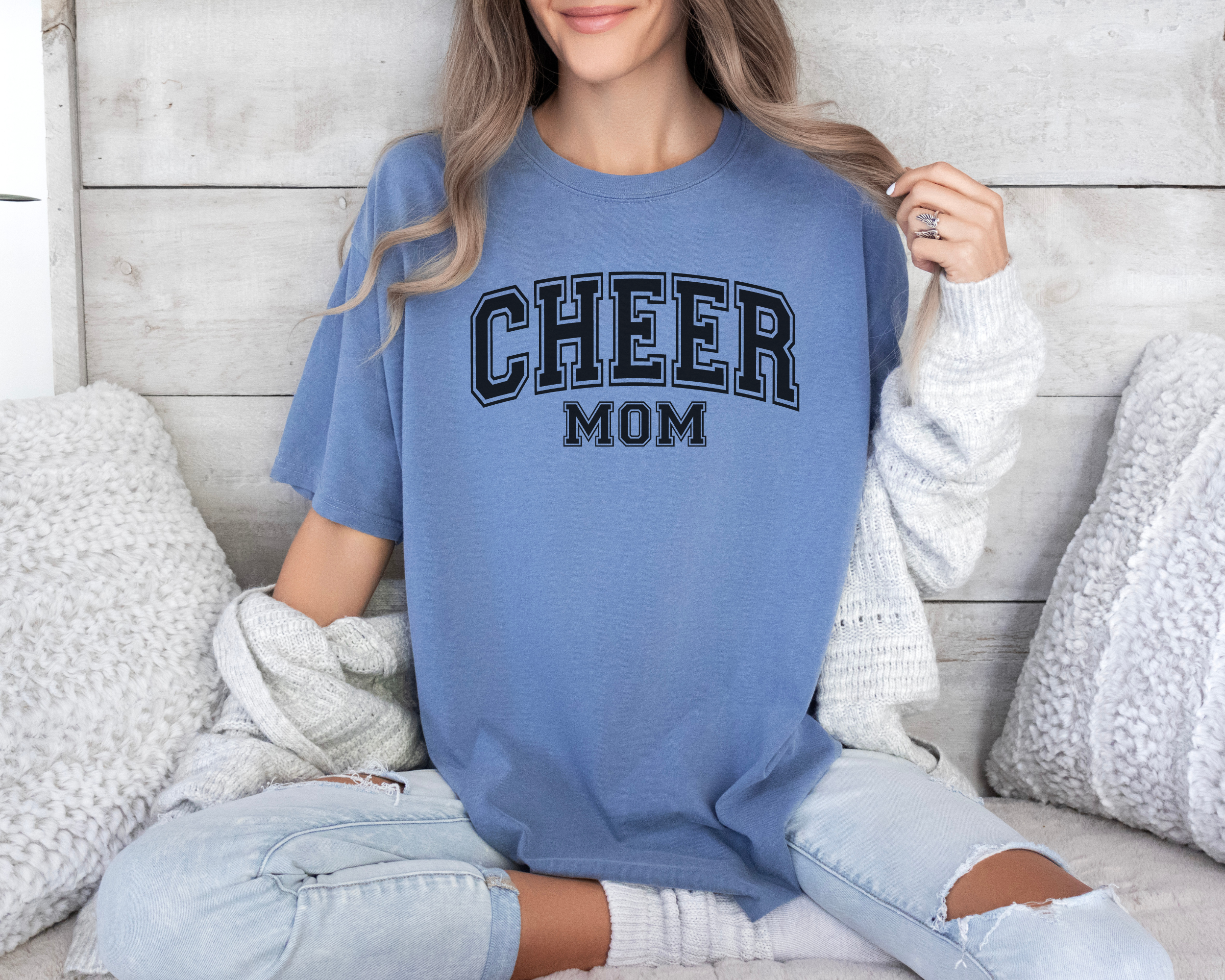Cheer mom shirt in a college outline text in the color blue with a black design.