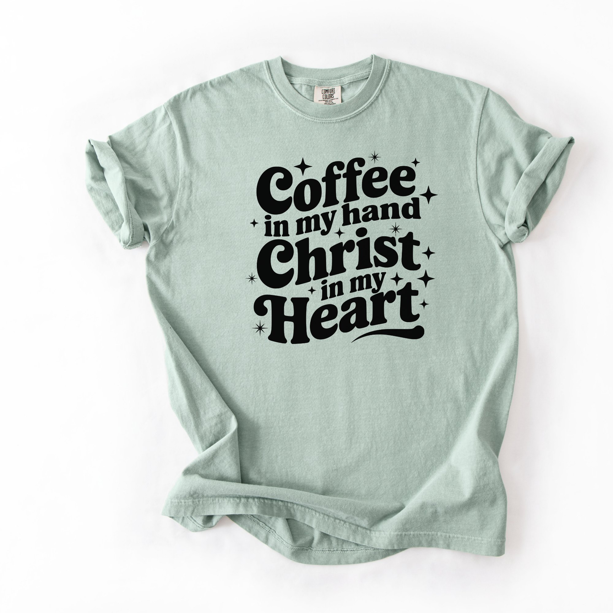 Bay or light green tee with black text that says "coffee in my hand christ in my heart." This shirt is meant for women who love Jesus and coffee.