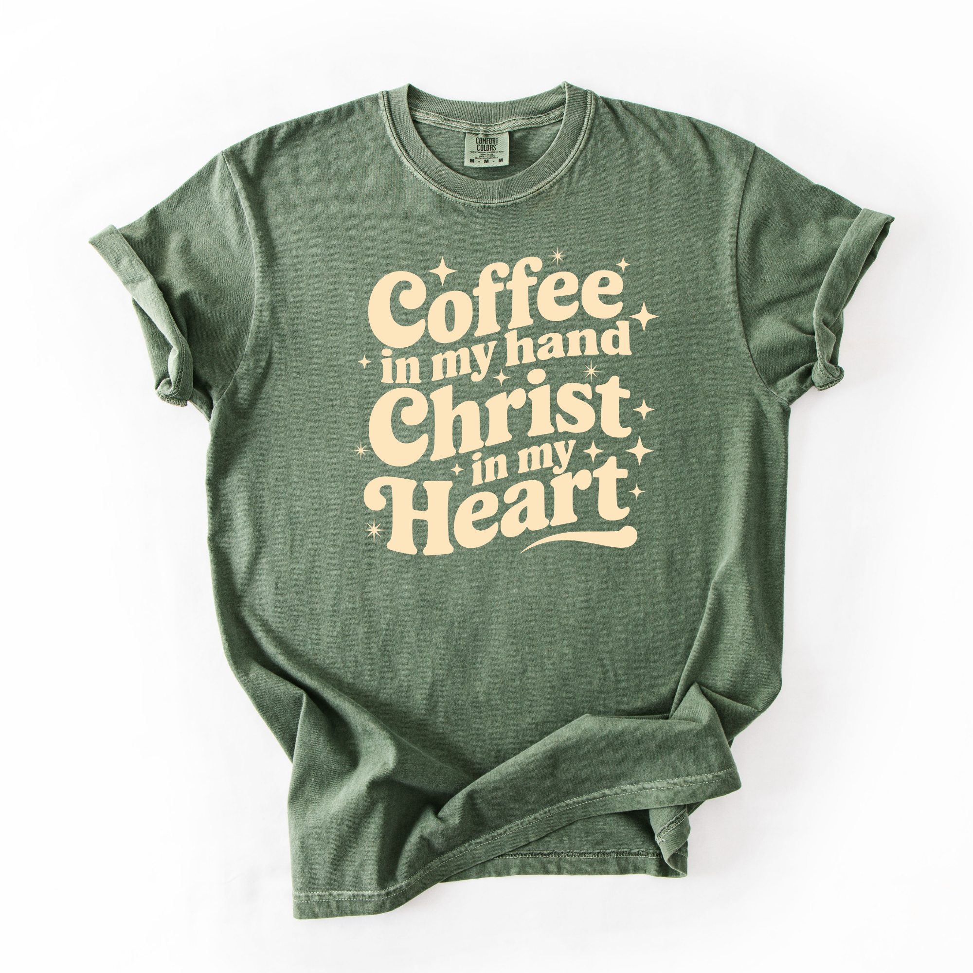 Moss, or medium toned green tee with beige text that says "coffee in my hand christ in my heart." This shirt is meant for women who love Jesus and coffee.