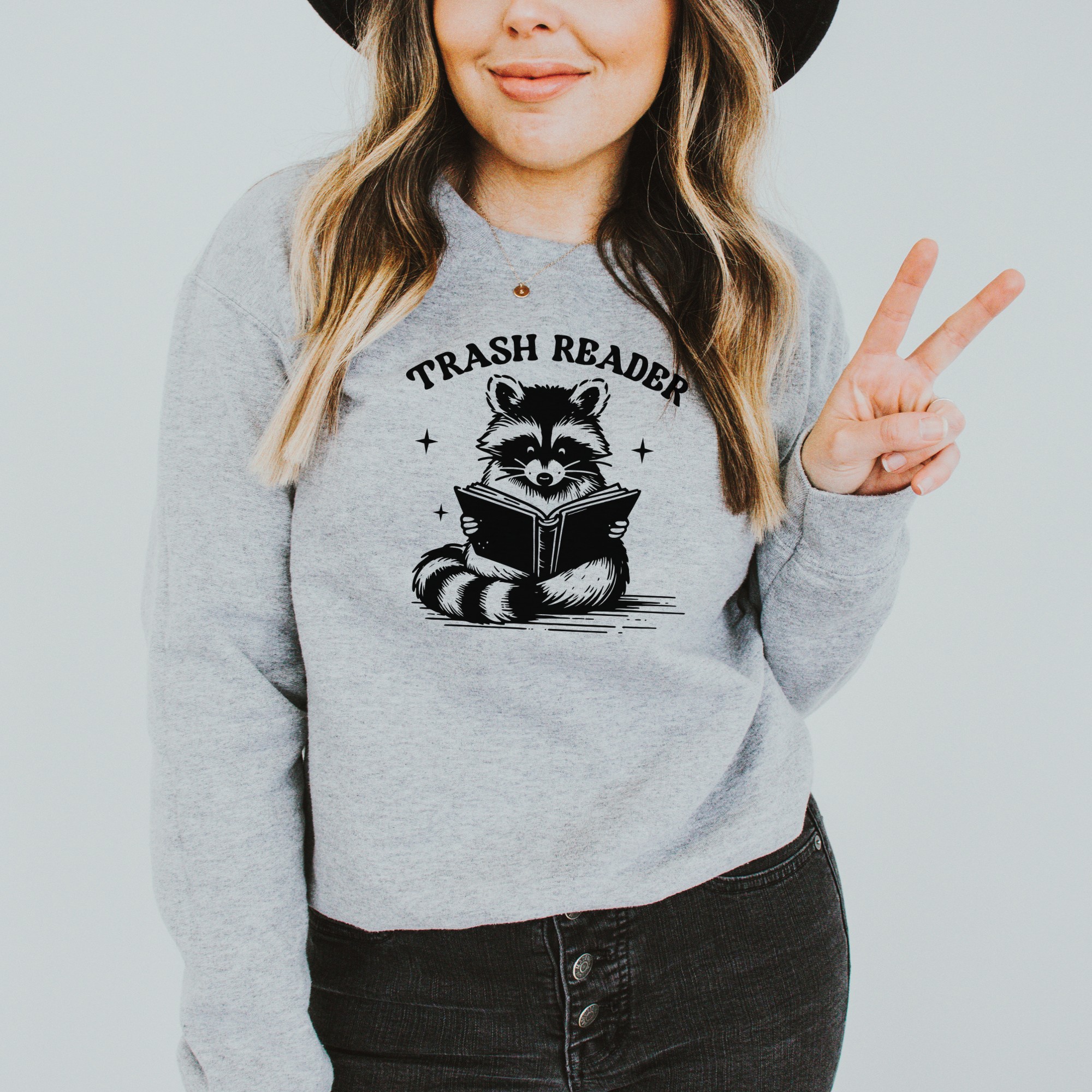 Trash reader with a raccoon reading a book.  The design is black and sweatshirt color is gray.