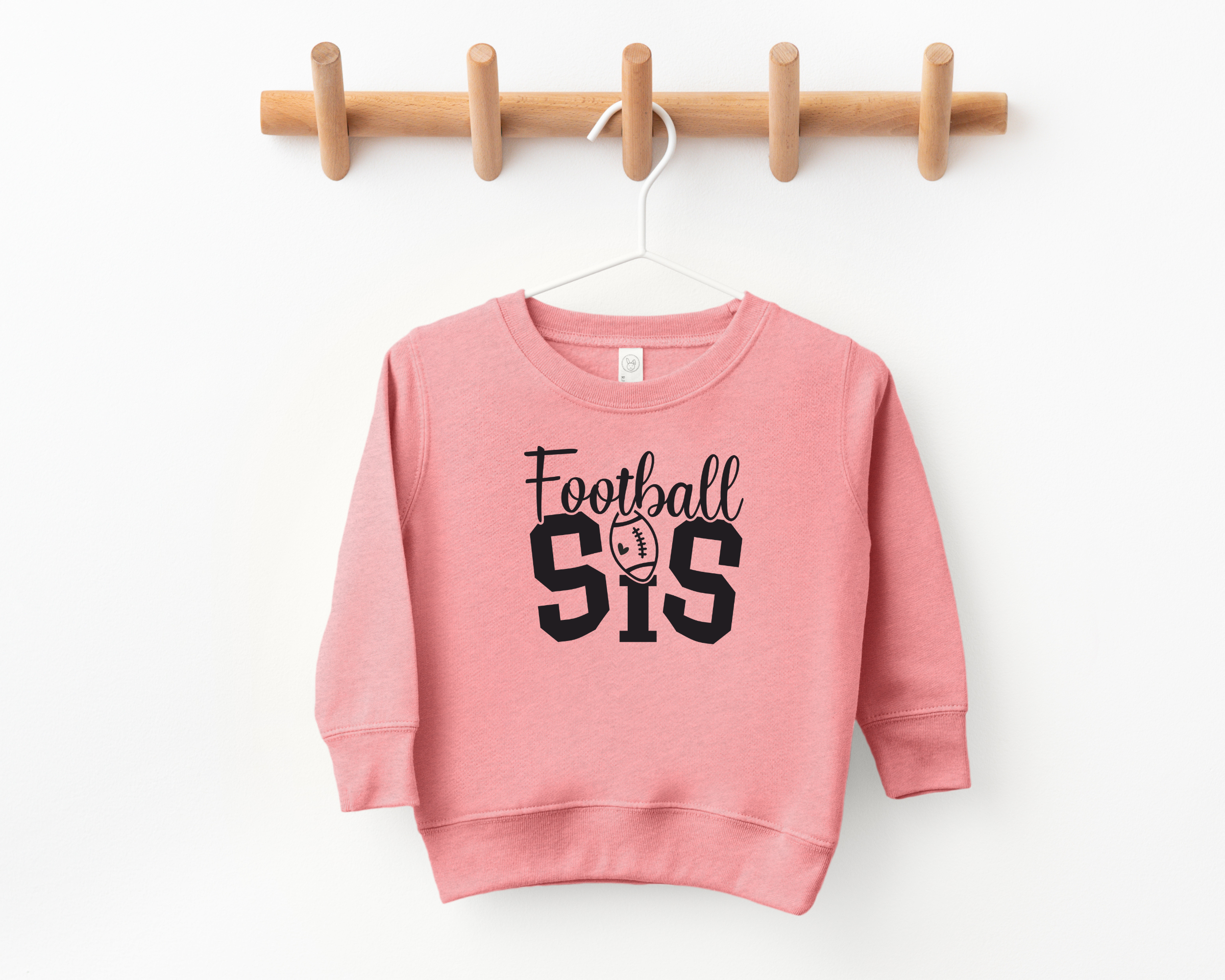 football sister sweatshirt in mauve with black design.  It says Football in cursive and below in college font it says sis and instead of a dot aboe the I it is a football with a cute heart inside.