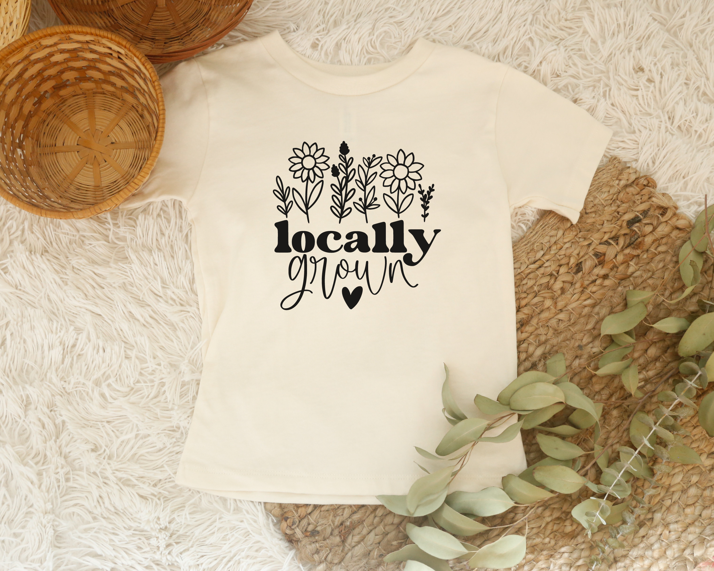 Cute kids graphic tee in the color natural with a black design.  The design is wildflowers and below it says locally grown with a heart below it.  The shirt is great for spring or summer.