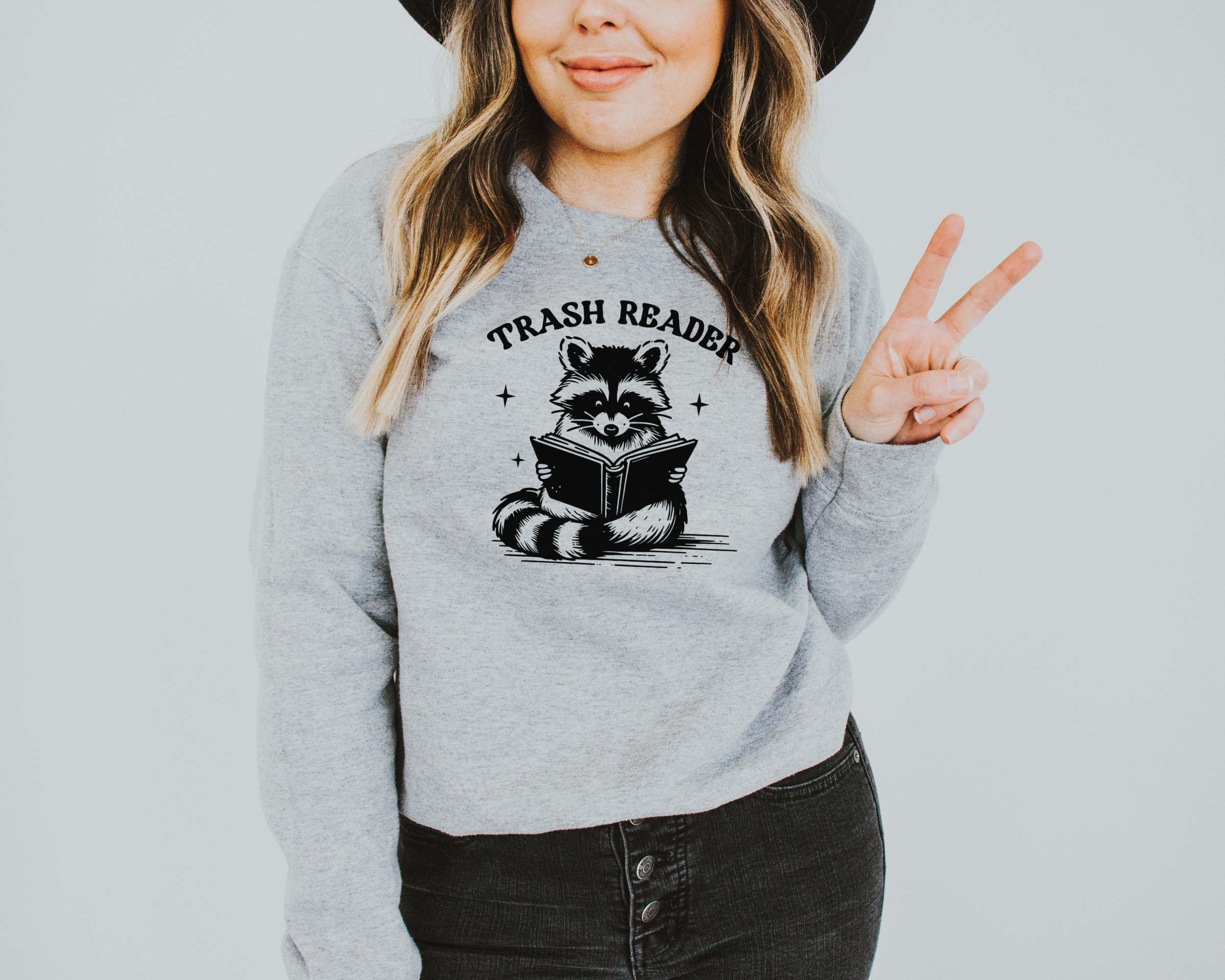 Trash reader with a raccoon reading a book.  The design is black and sweatshirt color is gray.